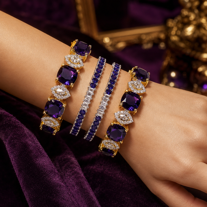 A close-up of a person's wrist wearing three ornate bracelets: two gold bracelets with large purple gemstones and clear stones, and one silver bracelet with dark blue gemstones. The background features a deep purple velvet fabric and a blurred gold decorative frame.